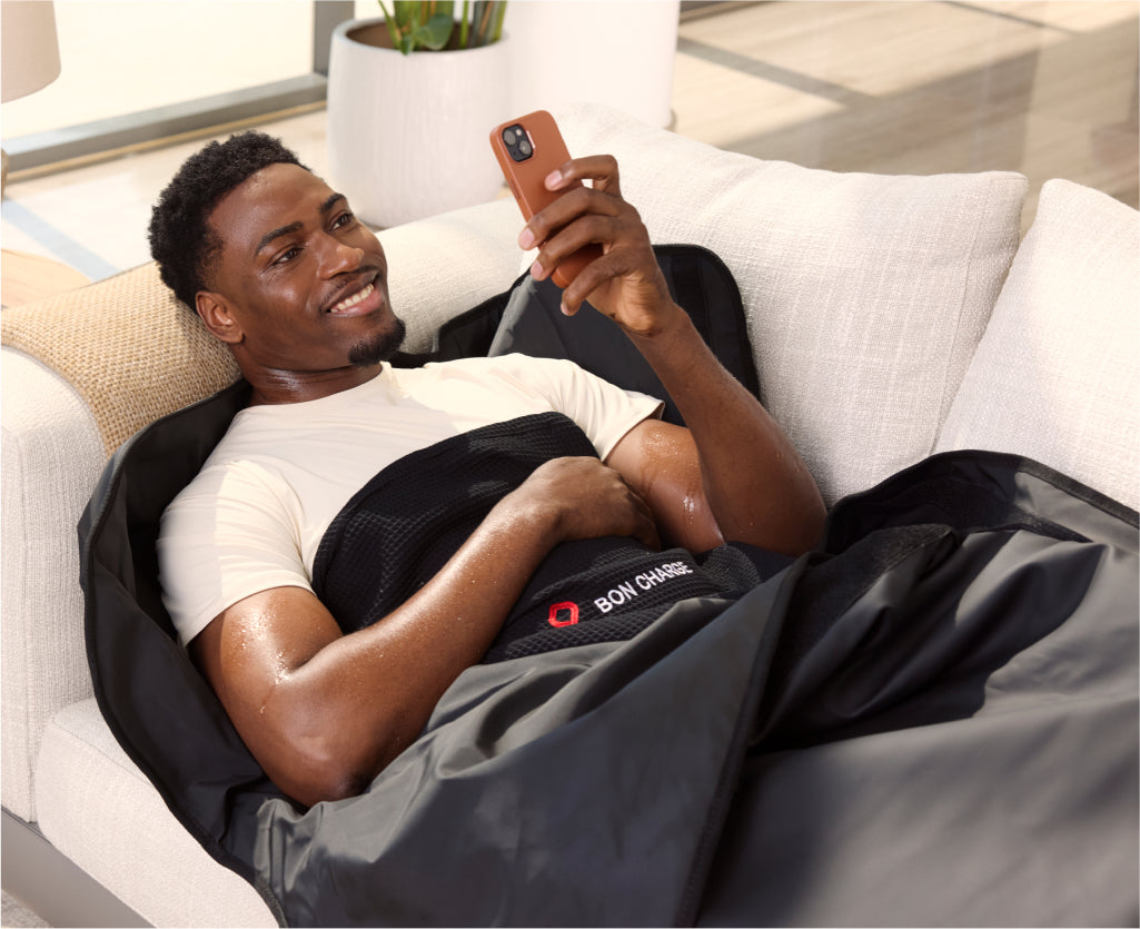 Male Laying On Sofa In Sauna Blanket Scrolling On Phone