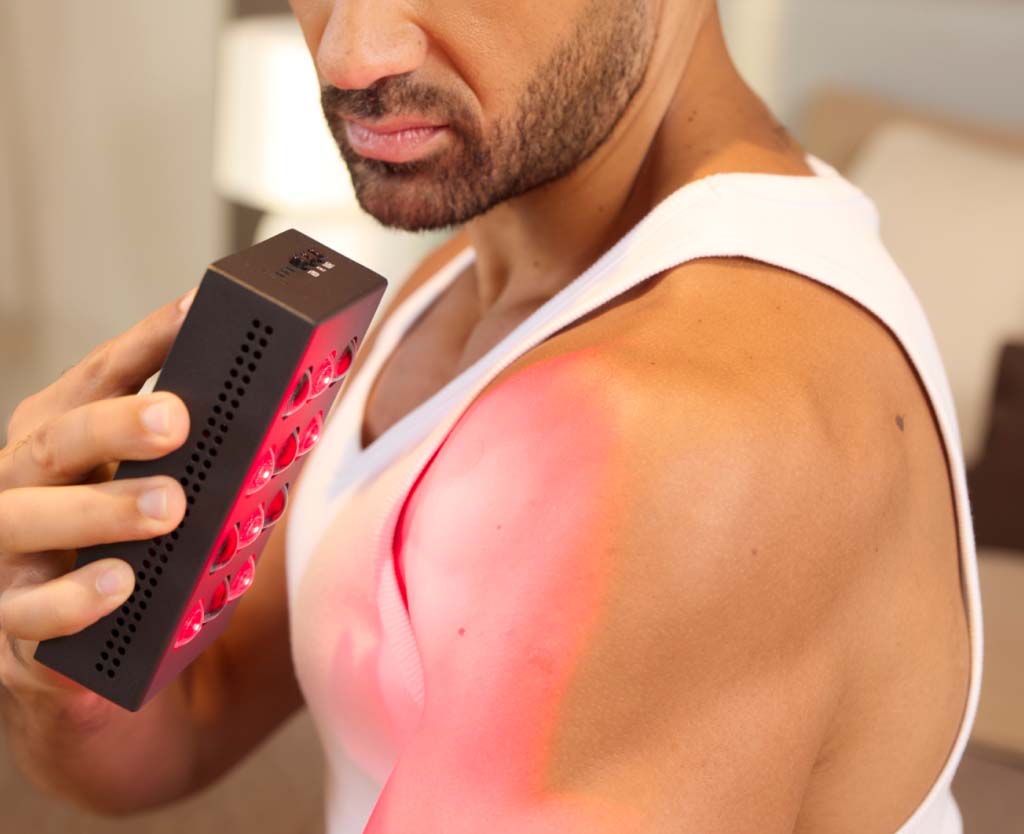 Man Holding Mini Red Light Device To Shoulder
